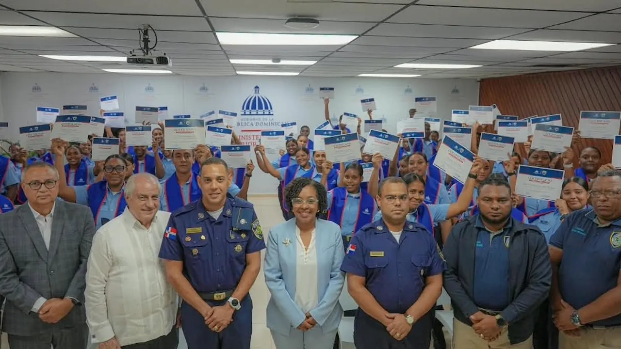 Grupo de jóvenes en uniforme policial sosteniendo diplomas junto a autoridades en un salón institucional.