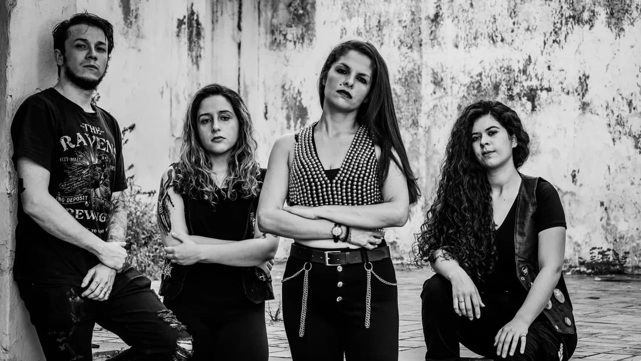 Cuatro integrantes de la banda de metal Bruja Maldita posan de pie y en cuclillas frente a una pared rústica.