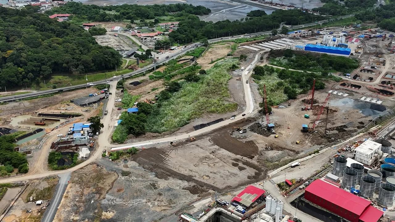 Vista aérea de maquinaria pesada y obras de excavación de túnel en un terreno despejado junto a una carretera.
