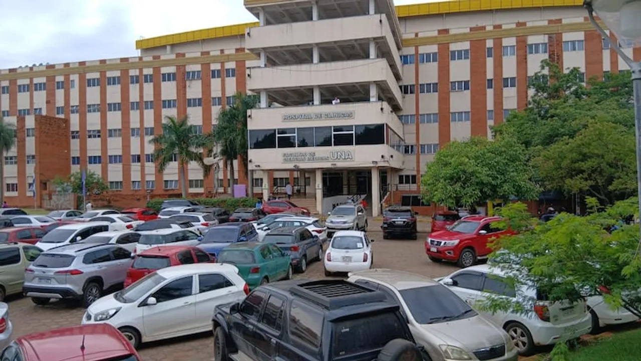 Edificio central del Hospital de Clínicas con un estacionamiento exterior ocupado por varios automóviles.