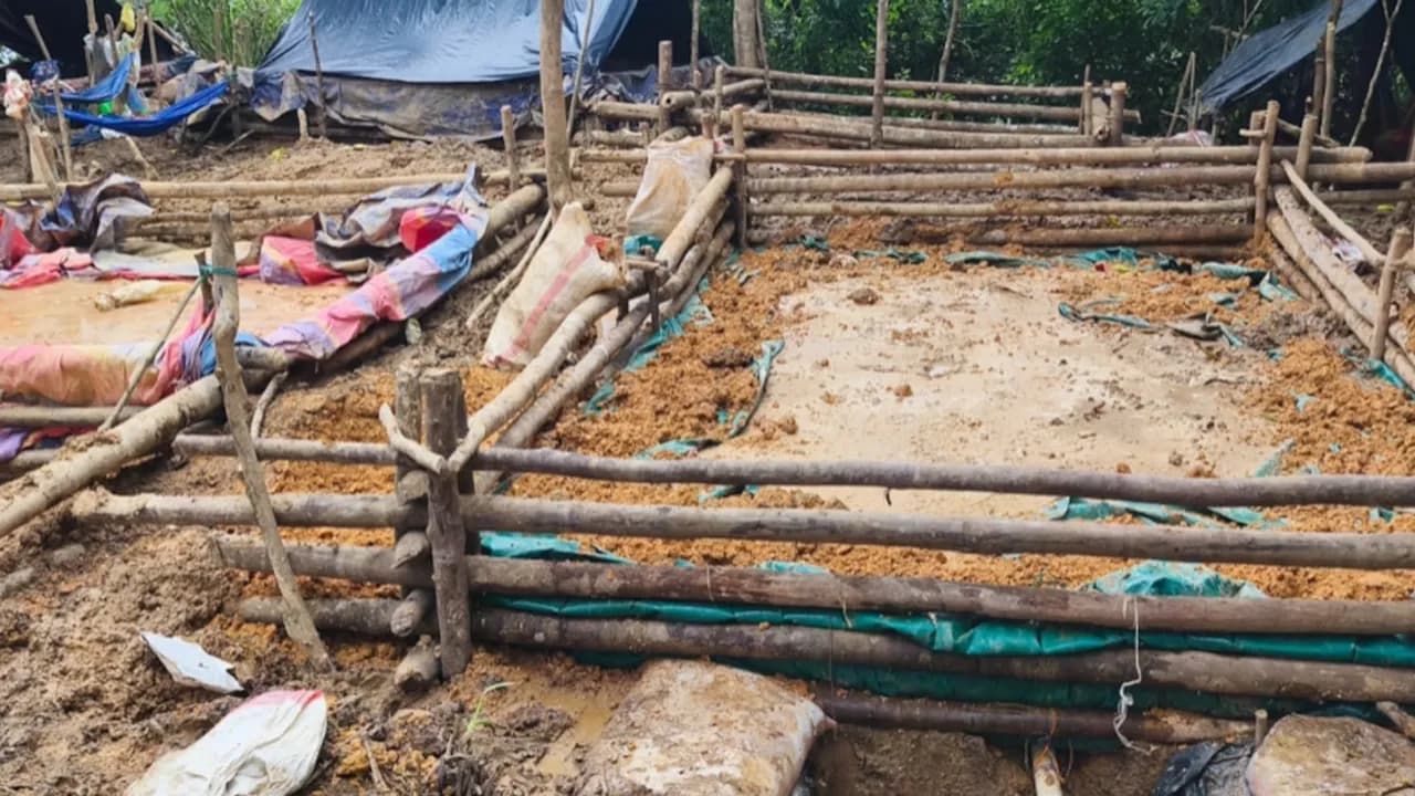 Estructuras rústicas de madera y plástico sobre fosas de tierra y lodo en un campamento de extracción minera.