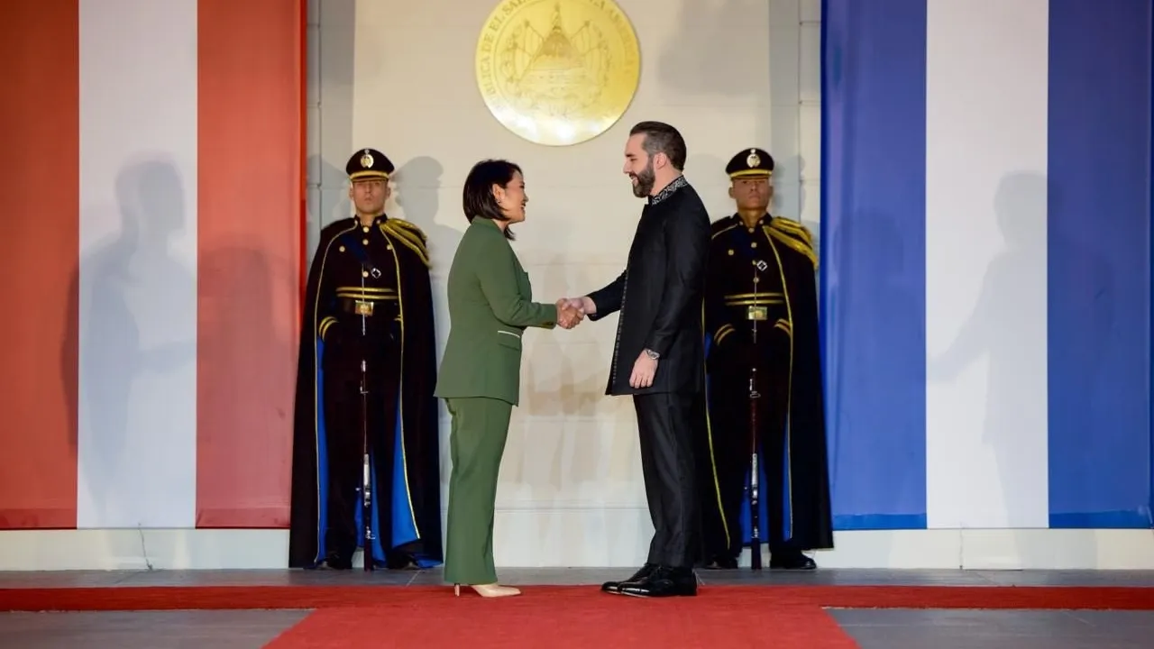 Dos mandatarios se estrechan la mano frente a escoltas militares de gala con banderas nacionales de fondo.