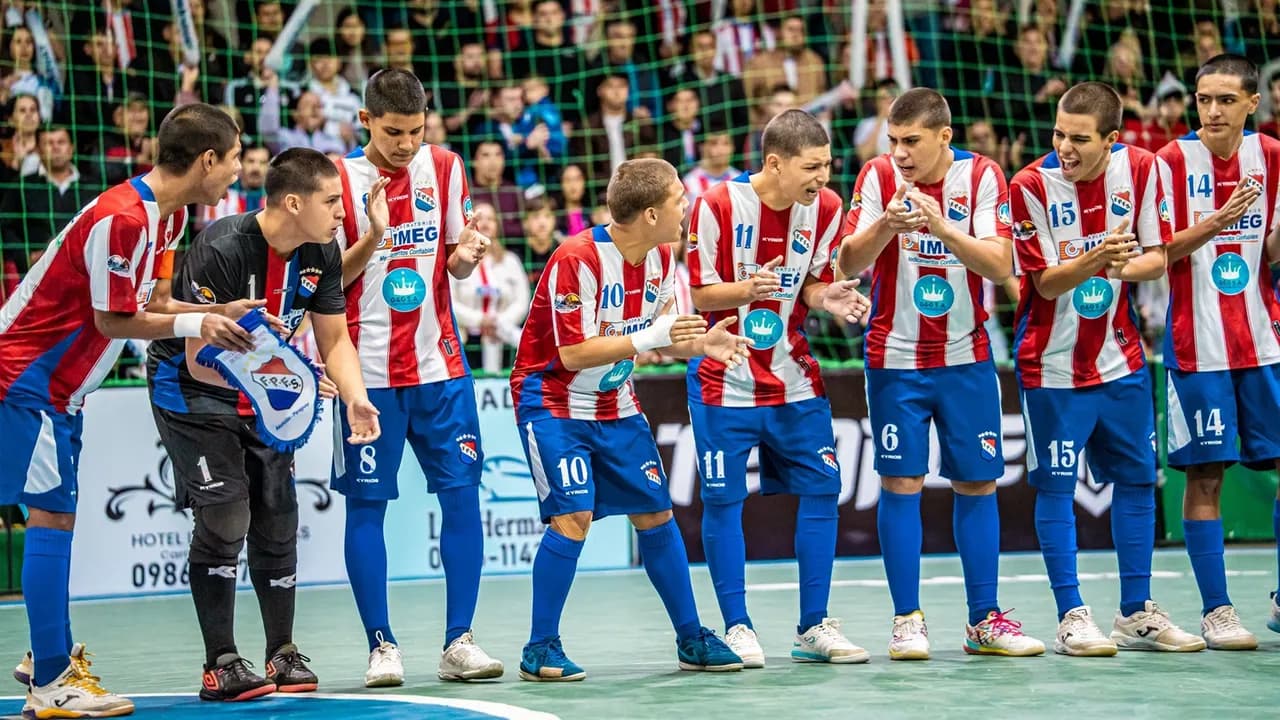 Jugadores de la selección paraguaya juvenil de fútbol de salón aplauden y celebran en la pista durante el torneo.