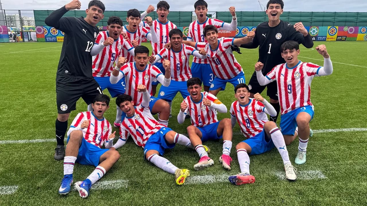Jugadores juveniles con camiseta albirroja festejan sonrientes y con los puños en alto sobre césped sintético.