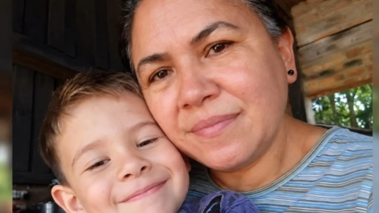 Primer plano de una mujer sonriente junto a un niño pequeño de cabello castaño claro en un entorno rural.