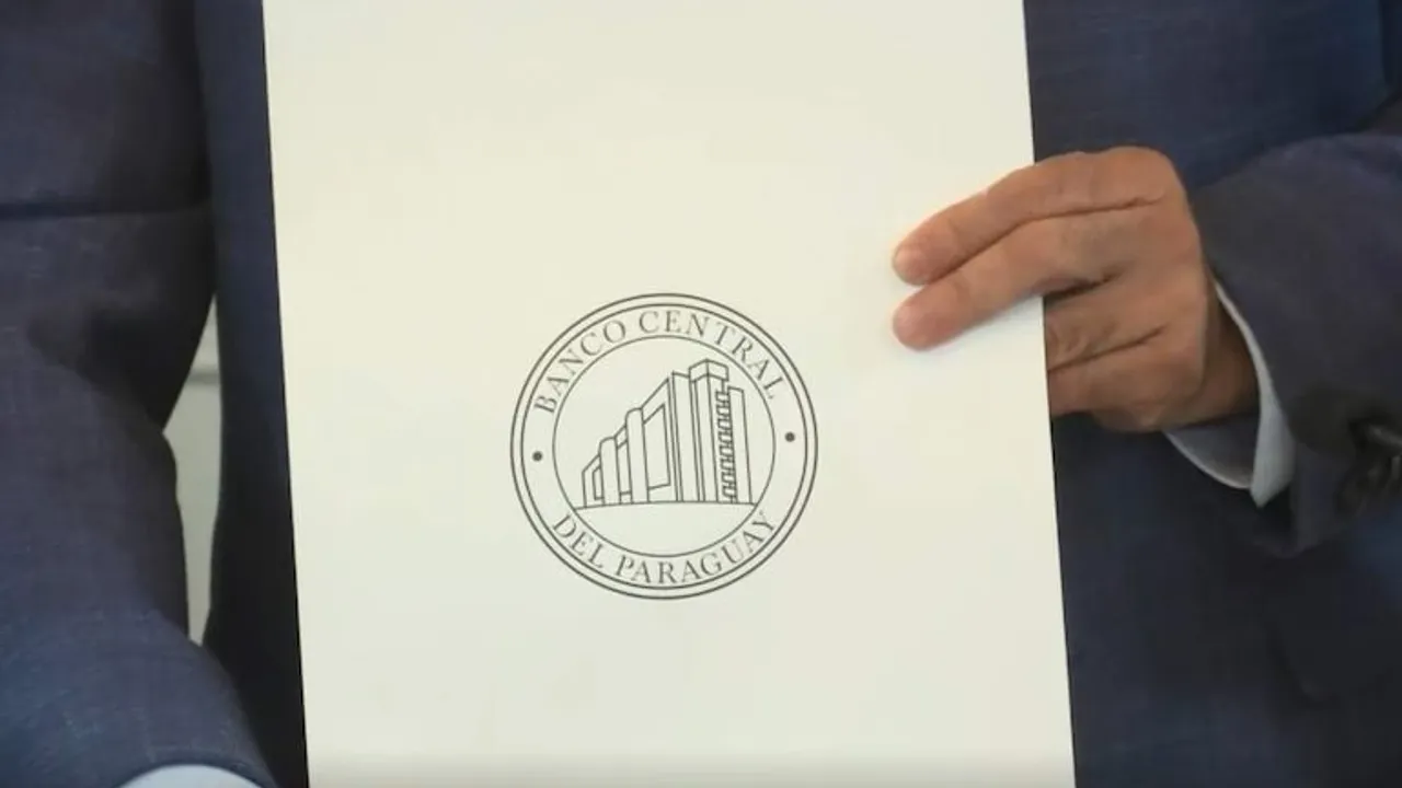 Persona sosteniendo una carpeta blanca con el sello circular impreso del Banco Central del Paraguay en primer plano.