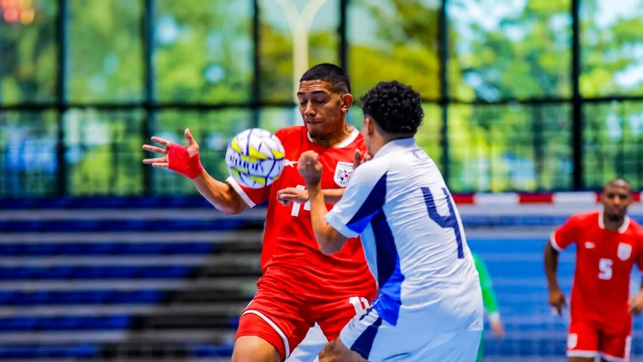 Jugador con uniforme rojo disputa el balón con la mano vendada frente a un rival con casaca blanca en una pista de futsal.