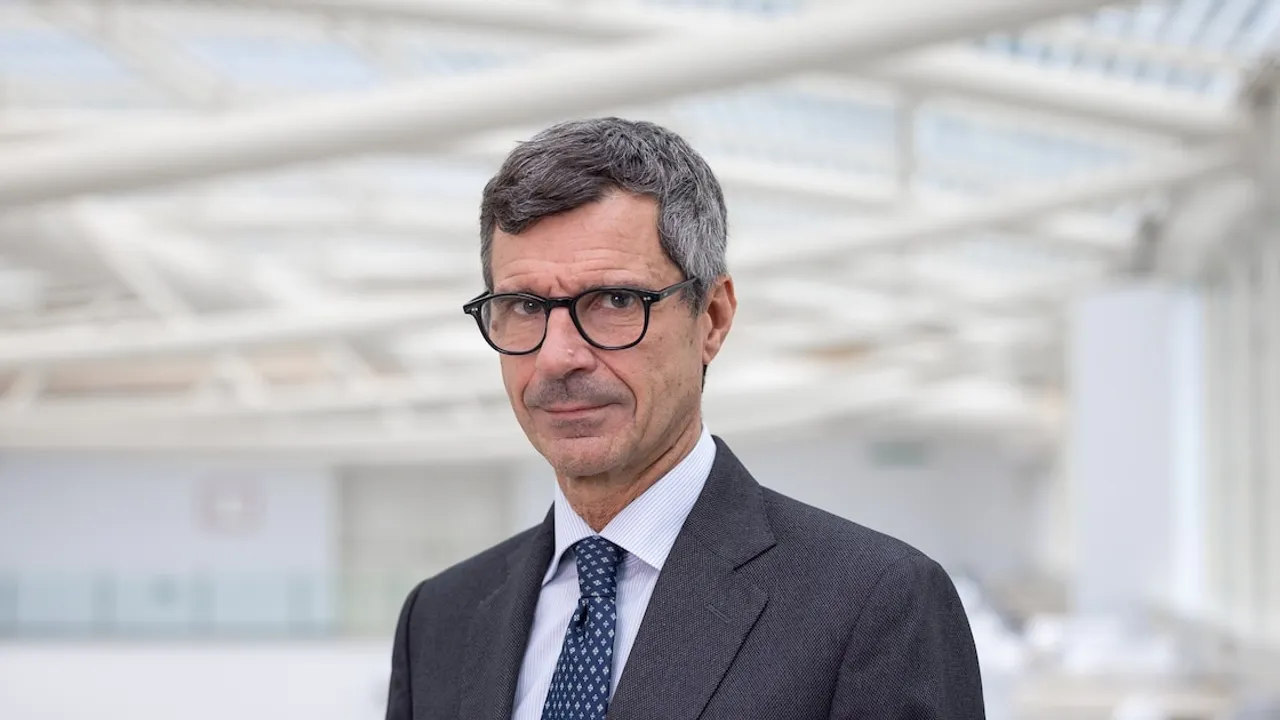 El médico Stefano Margaritora con anteojos oscuros, traje formal y corbata en un espacio amplio