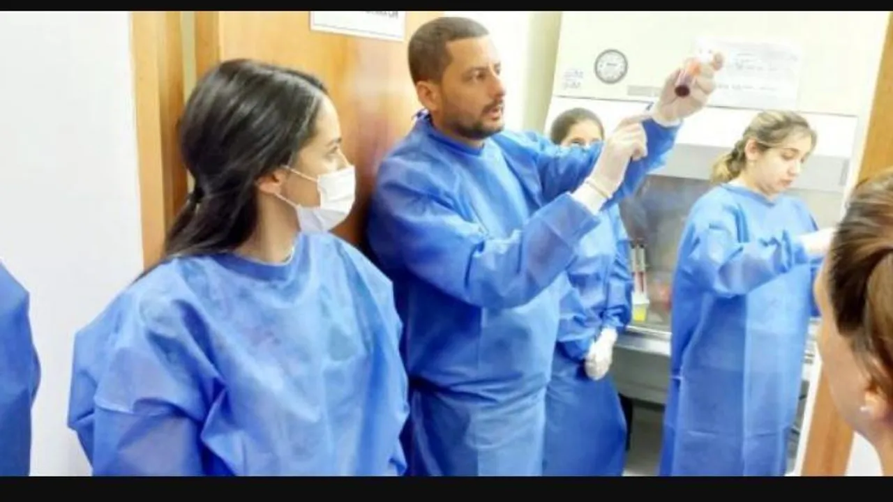 Personal de salud con batas y tapabocas examinando un tubo de ensayo dentro de un laboratorio.