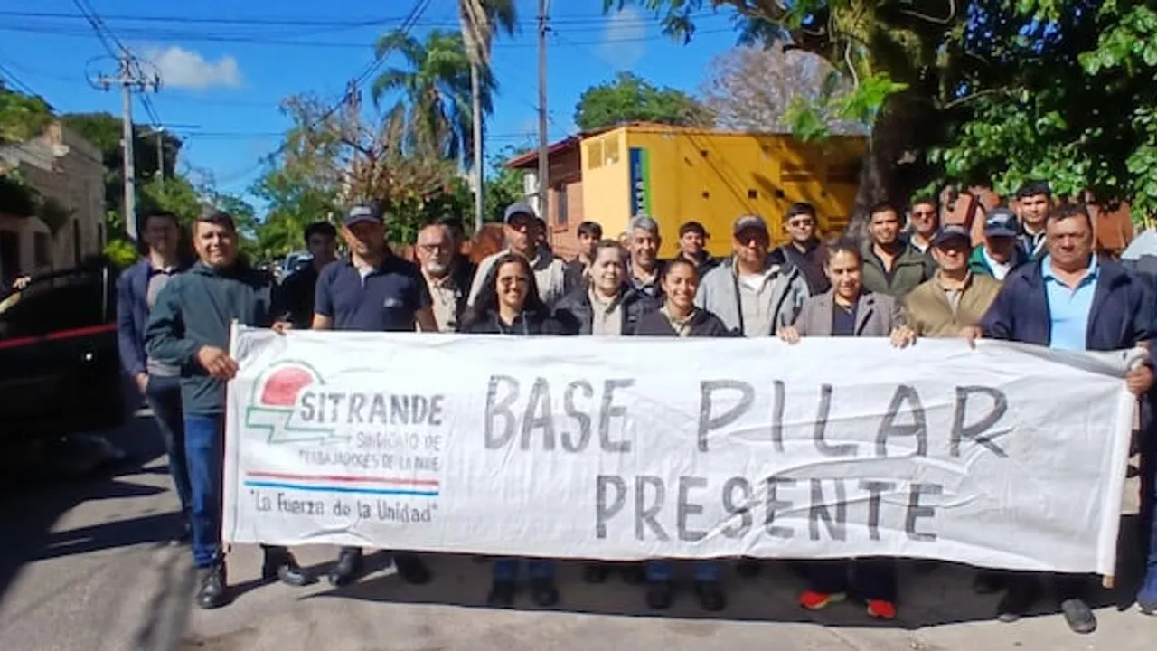 Grupo de funcionarios sostiene un pasacalle del sindicato Sitrande en la vía pública frente a una sede.