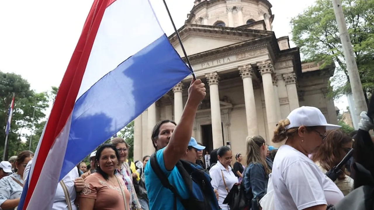 Manifestantes sostienen una bandera paraguaya frente al Panteón Nacional de los Héroes en el centro de Asunción.