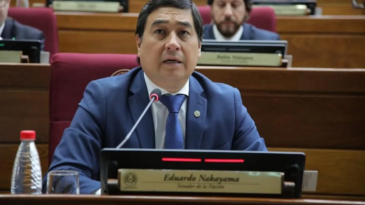 Eduardo Nakayama con traje azul habla ante el micrófono en su banca durante una sesión del Senado paraguayo.