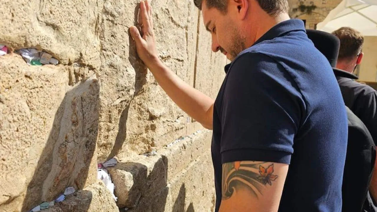 Pedro Alliana apoya su mano derecha sobre los bloques de piedra del Muro de los Lamentos, con notas de oración.