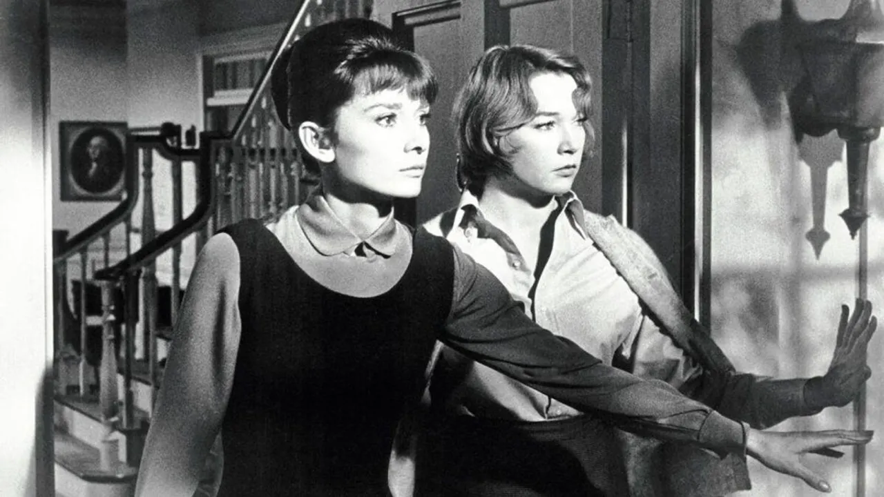 Dos mujeres con peinados de época observan con expresión tensa el interior de una casa en blanco y negro.