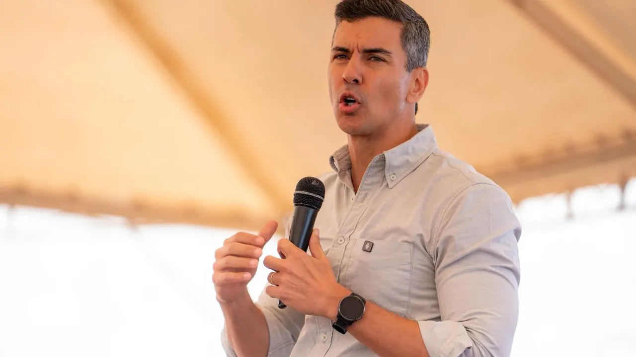 Santiago Peña hablando con un micrófono en mano durante un evento oficial al aire libre.