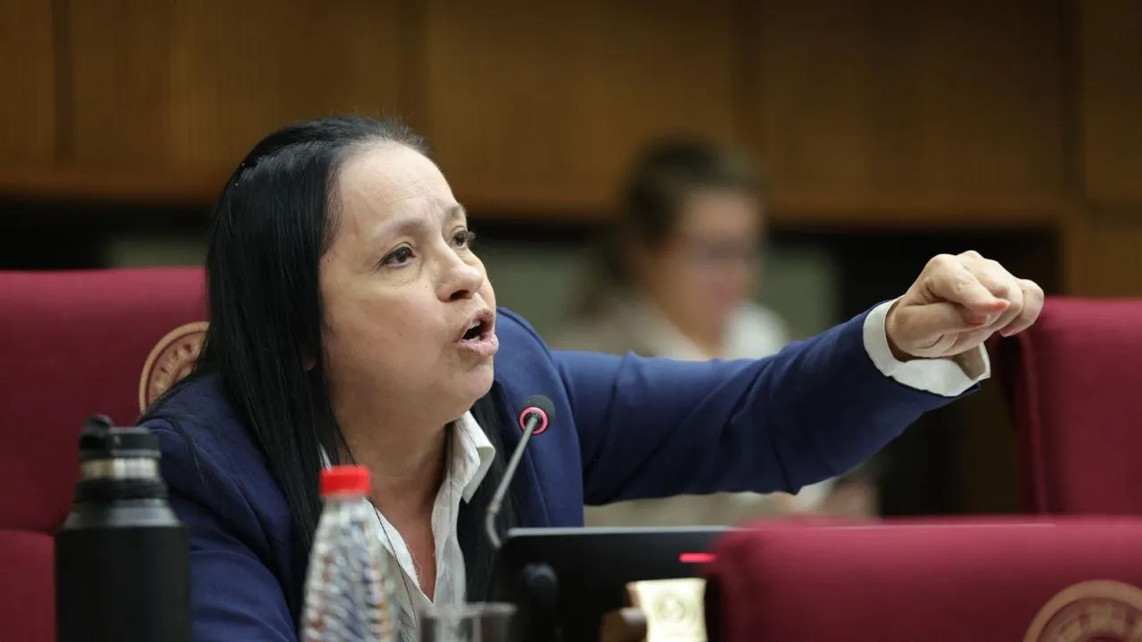 Senadora Yolanda Paredes sentada en su banca del Congreso habla al micrófono y señala con el dedo hacia adelante.