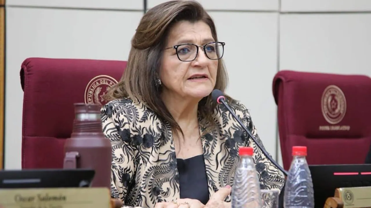 Mujer con lentes y traje oscuro con diseño beige habla frente al micrófono en una banca del Senado paraguayo.