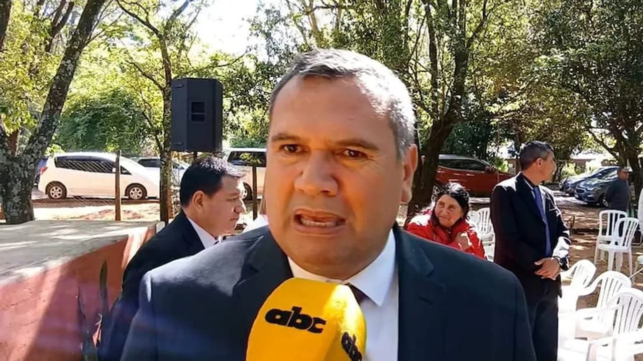 Derlis Maidana brinda declaraciones ante un micrófono de prensa en un espacio al aire libre rodeado de árboles.