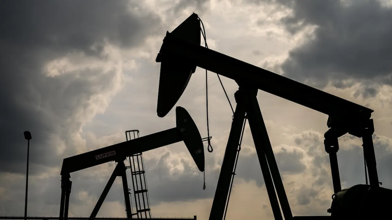 Siluetas de dos balancines de extracción de petróleo operando bajo un cielo nublado al atardecer.