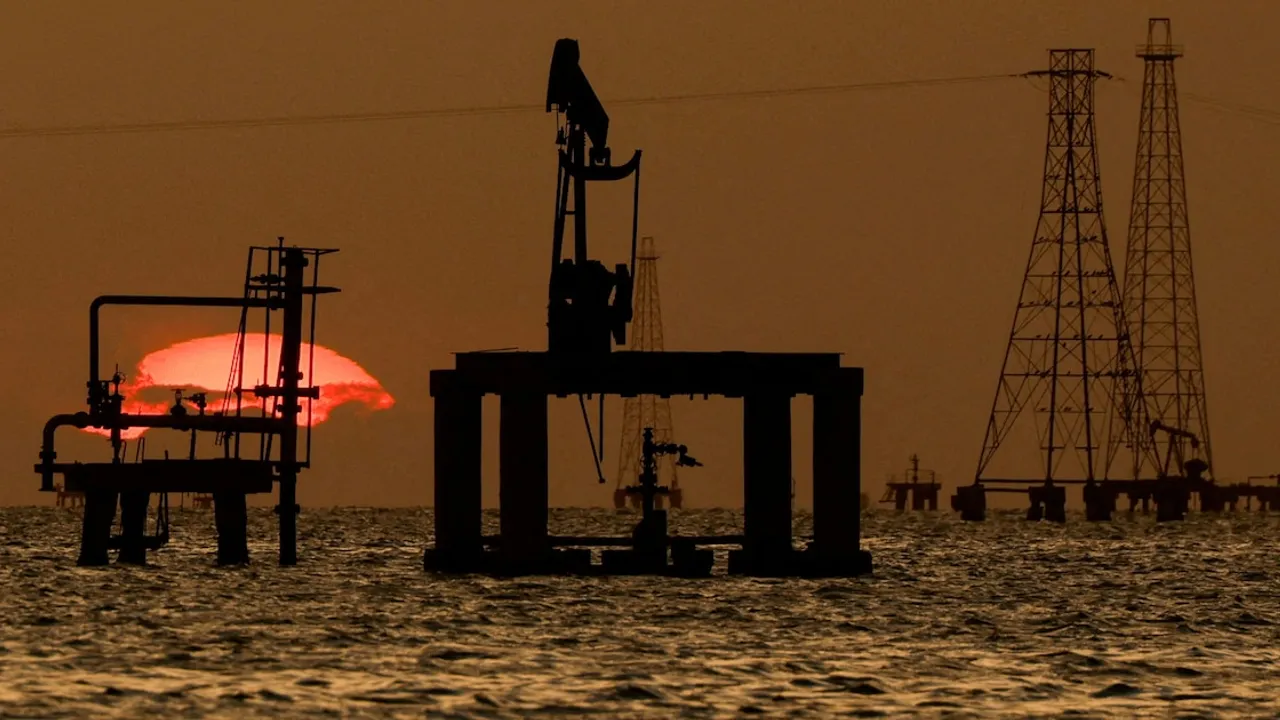 Instalaciones petroleras en el mar con siluetas de torres de extracción frente a un sol poniente