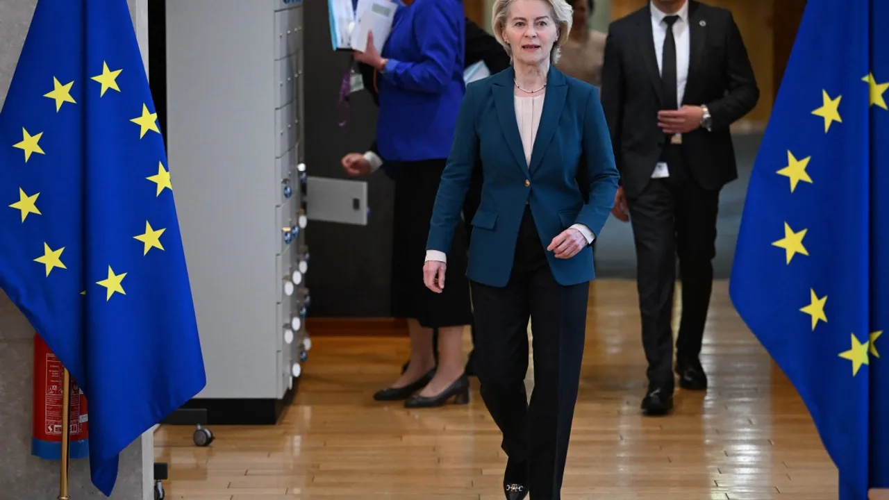 Ursula von der Leyen camina sonriente por un pasillo flanqueada por dos banderas de la Unión Europea.