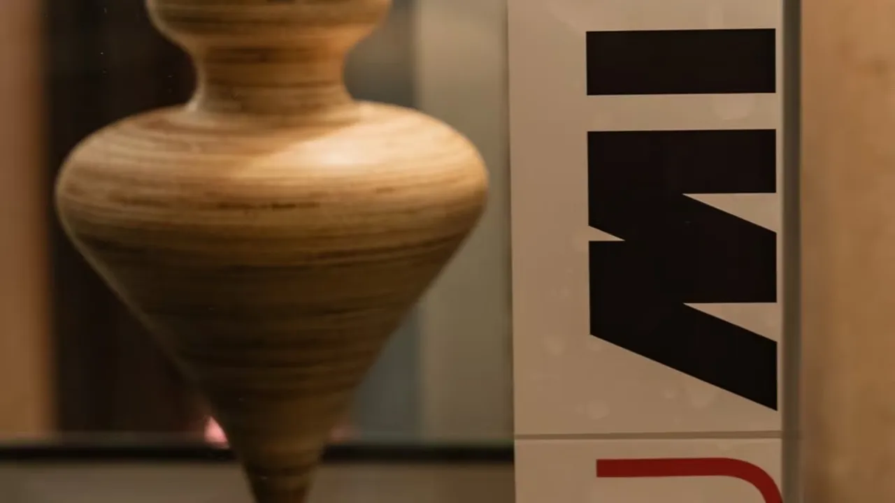 Trofeo de madera torneada en forma de trompo junto a un panel con letras negras