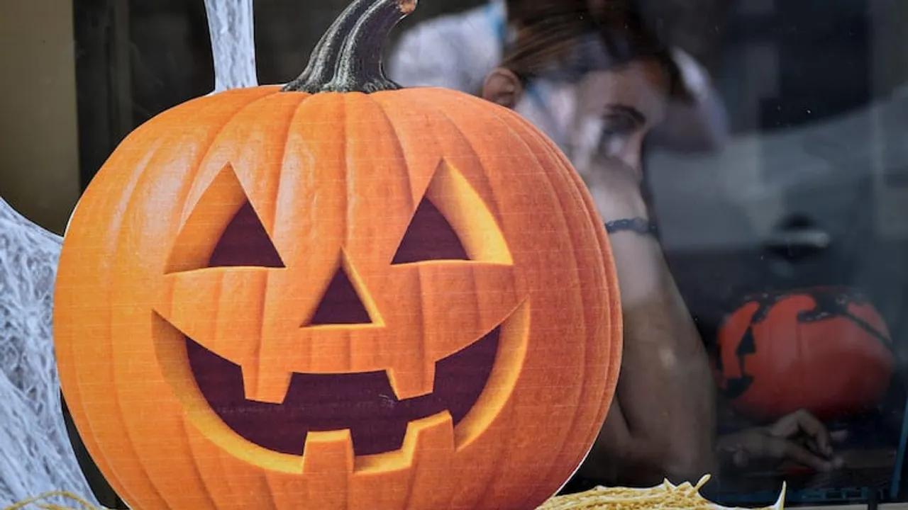 Calabaza decorativa de color naranja con rostro tallado expuesta detrás de un vidrio