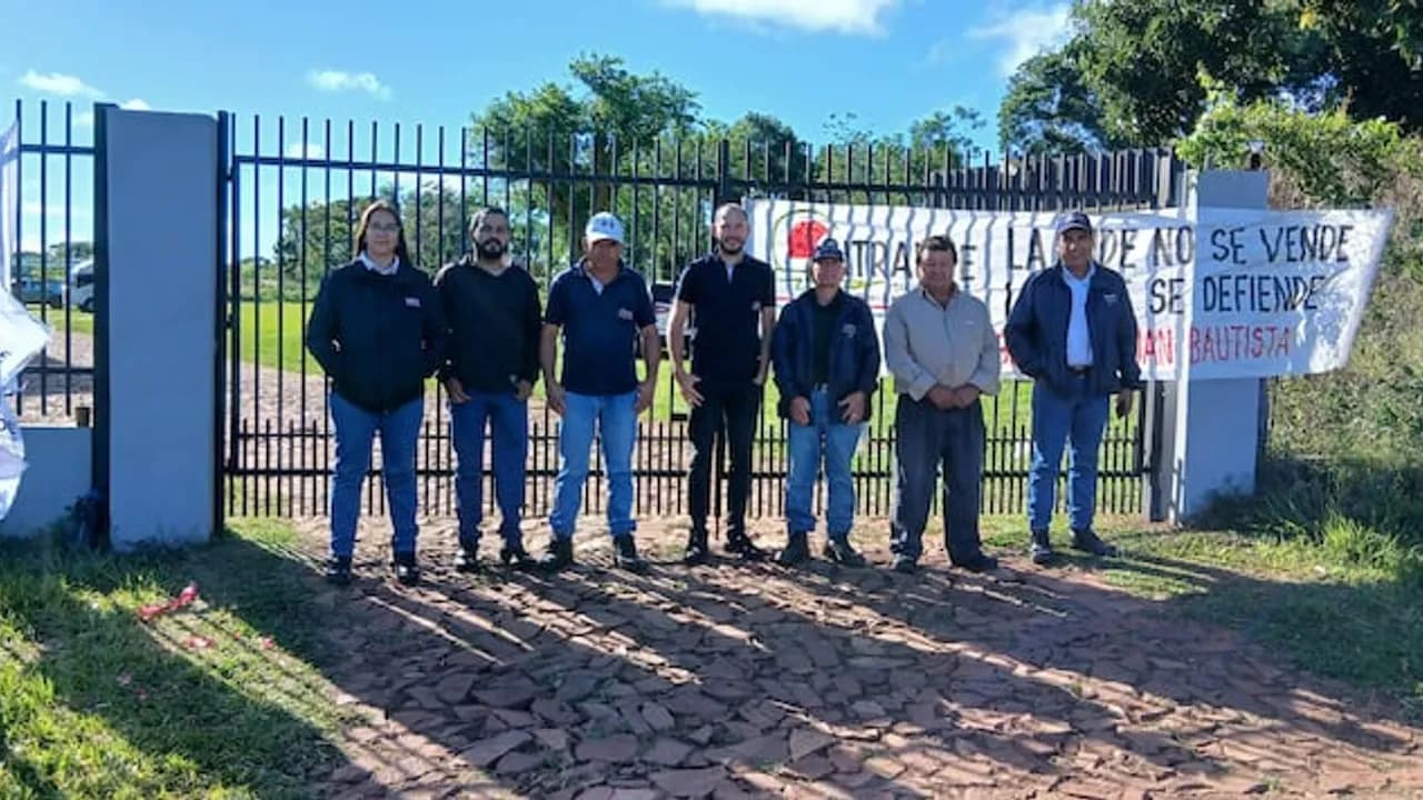 Grupo de funcionarios frente al portón de una sede sosteniendo un cartel de manifestación sindical