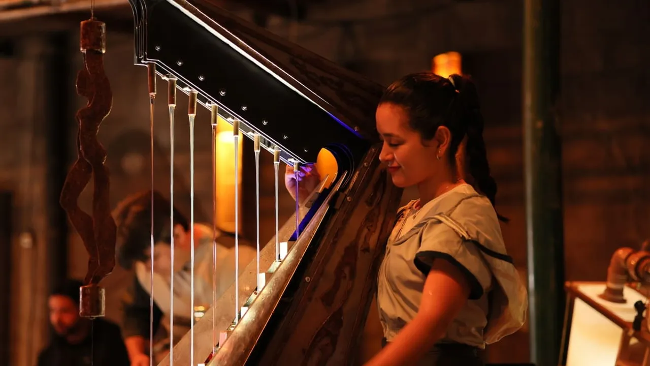Músico tocando un arpa experimental diseñada con tubos de agua durante una presentación artística nocturna.