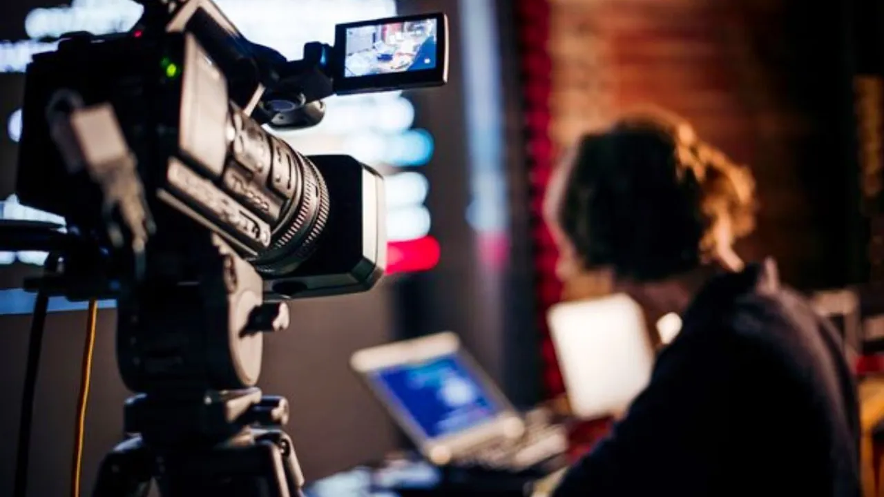 Cámara de filmación profesional montada sobre un trípode en un estudio de grabación con una persona al fondo