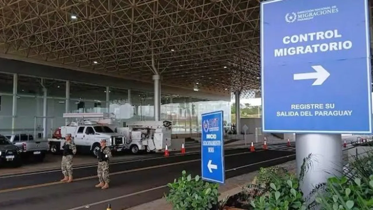 Cartel azul de control migratorio paraguayo frente a la estación fronteriza y agentes de seguridad uniformados.