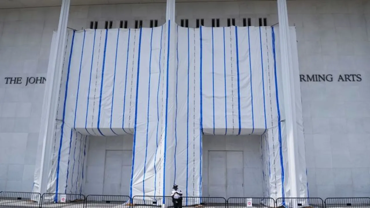 Entrada del Centro Kennedy cubierta con lonas blancas y franjas azules frente a una valla de seguridad.