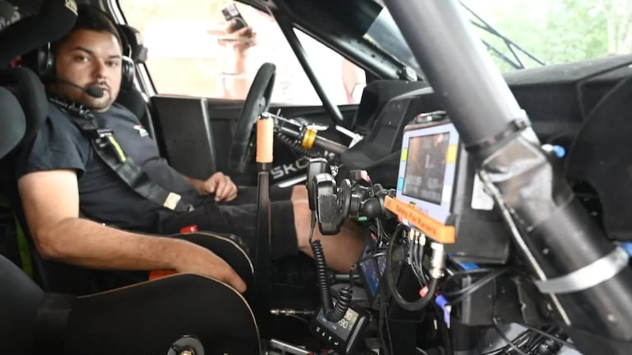 Piloto sentado dentro de un auto de competición equipado con barra antivuelco y pantalla de navegación satelital.