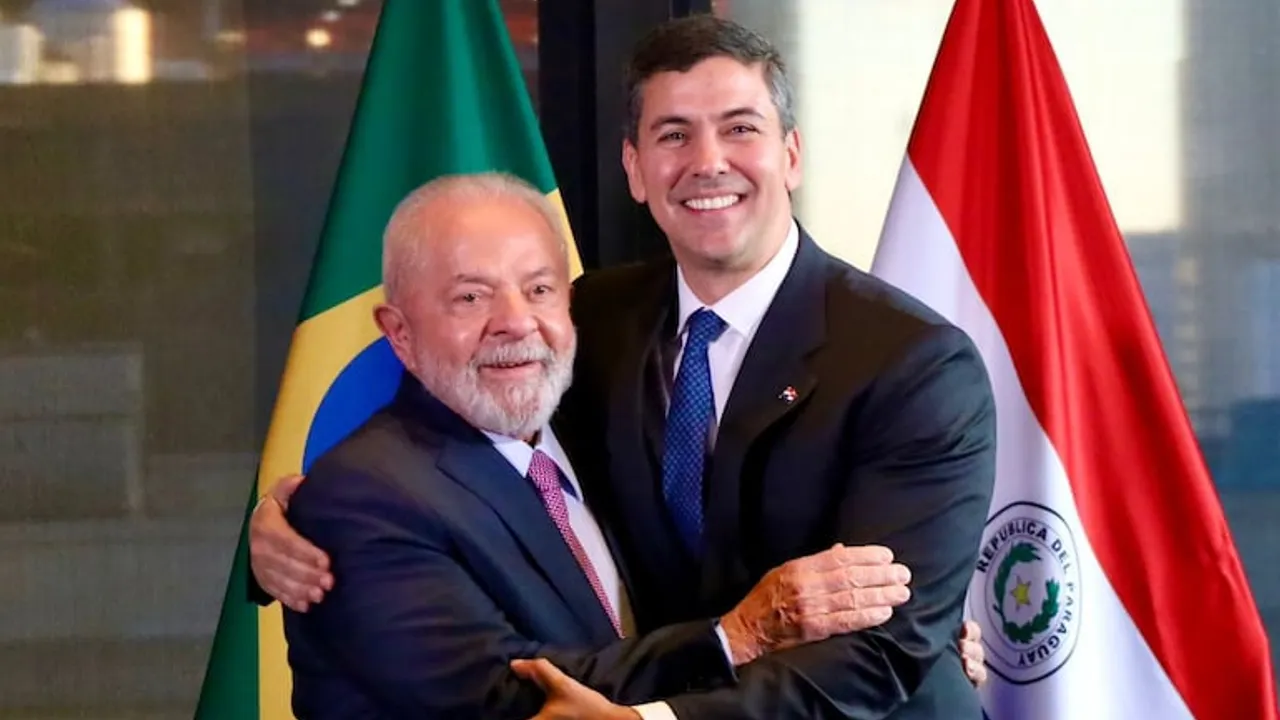 Santiago Peña y Luiz Inácio Lula da Silva se abrazan sonrientes frente a las banderas de Paraguay y Brasil.