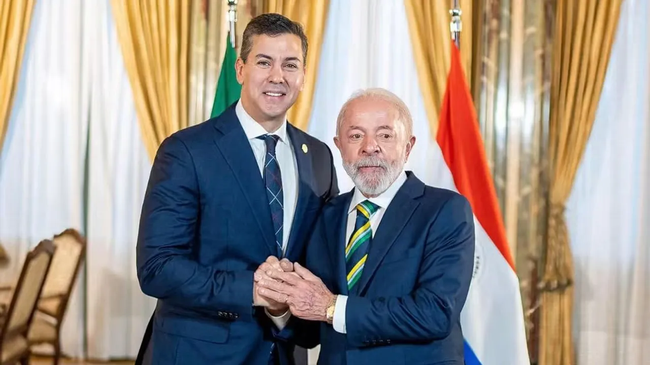 Santiago Peña y Luiz Inácio Lula da Silva se estrechan las manos vestidos de traje frente a banderas oficiales.