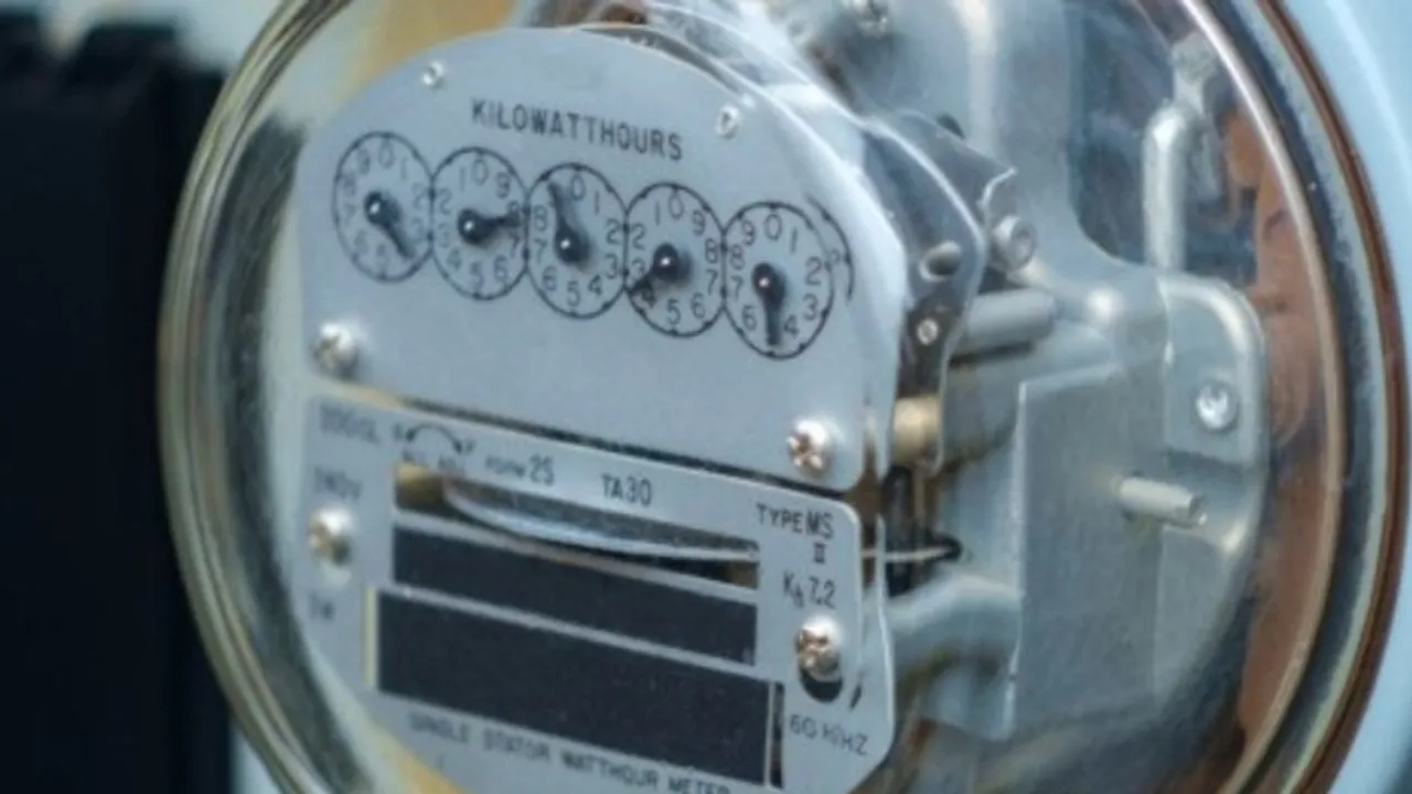 Primer plano de un medidor analógico de electricidad con engranajes, esfera de cristal y lectura en kilovatios hora.