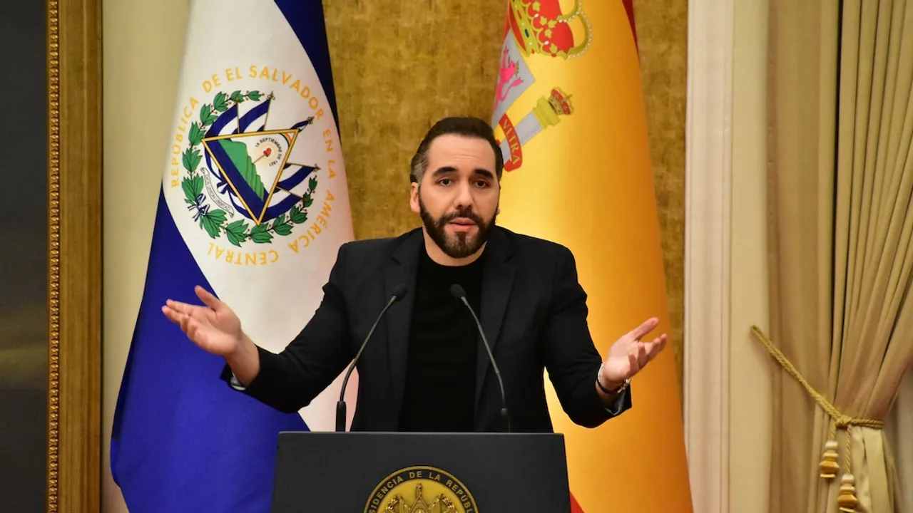 Nayib Bukele habla desde un atril oficial con las manos abiertas, frente a banderas nacionales.