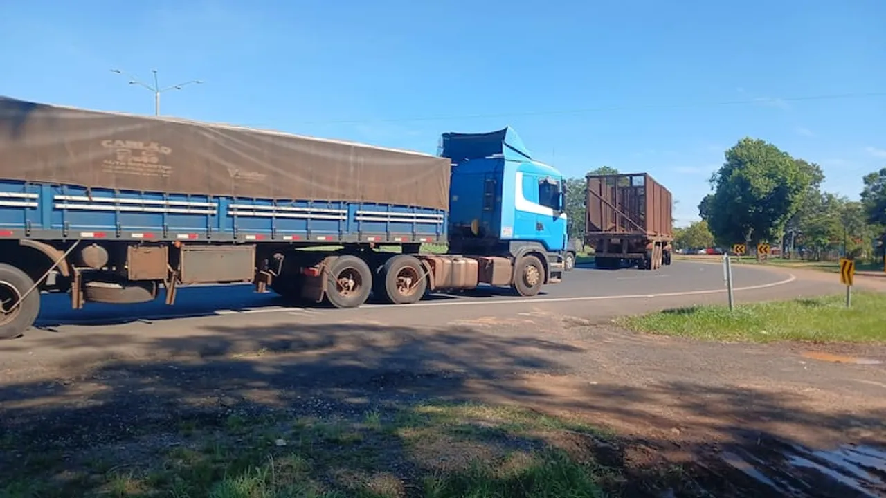 Dos camiones de gran porte circulan por una curva asfaltada de una ruta bajo la luz del día.
