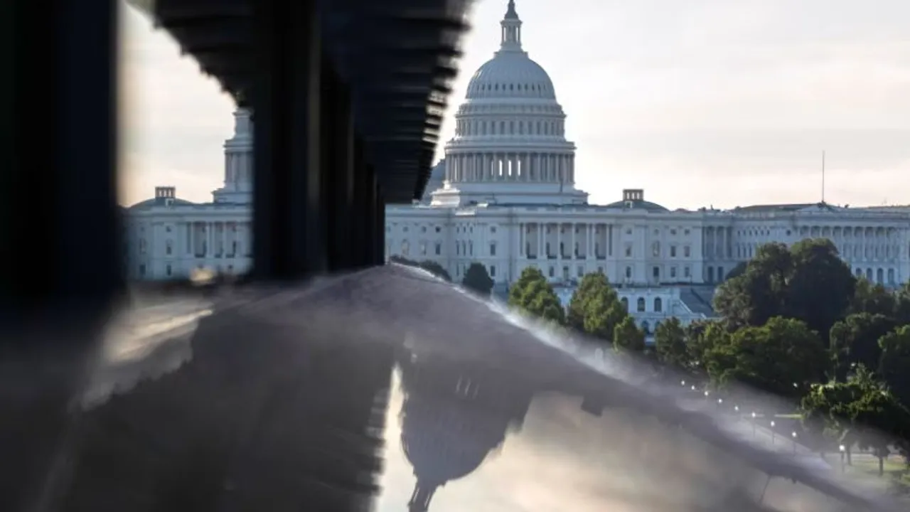 Cúpula blanca del Capitolio de Estados Unidos reflejada en una superficie de vidrio con barandilla metálica.