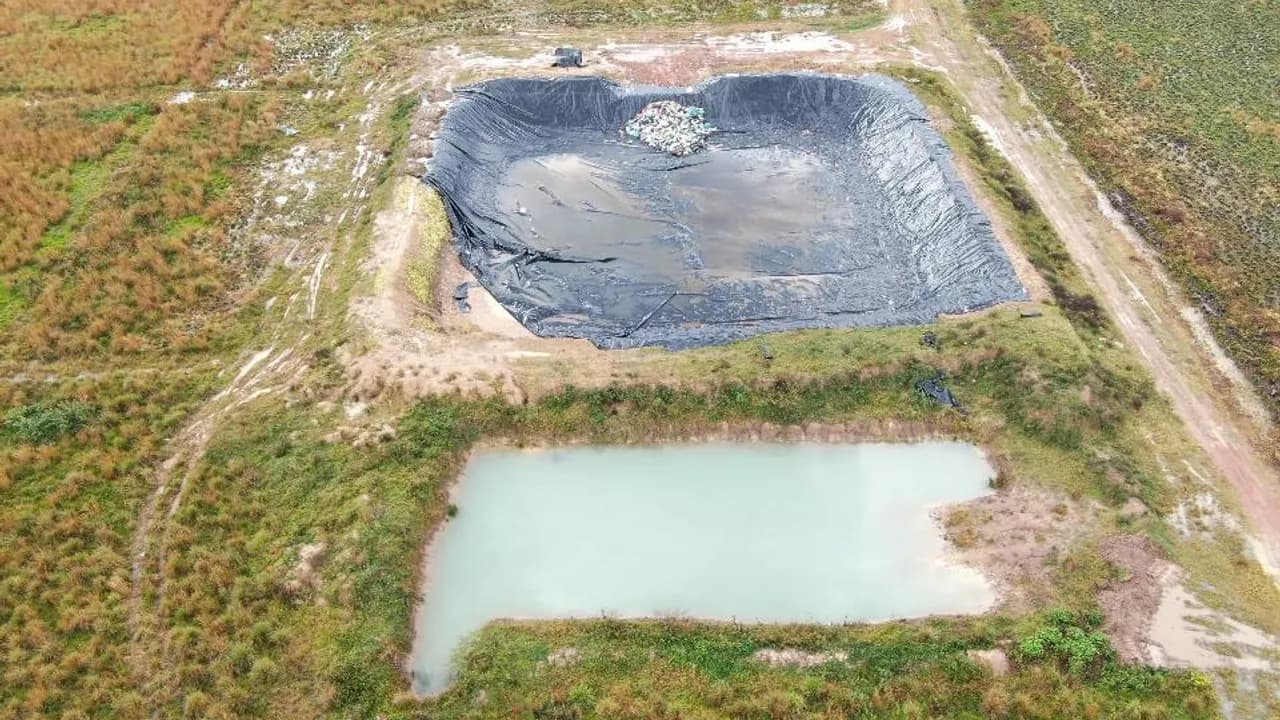 Vista aérea de fosas excavadas para vertedero con geomembrana plástica y una laguna artificial al lado