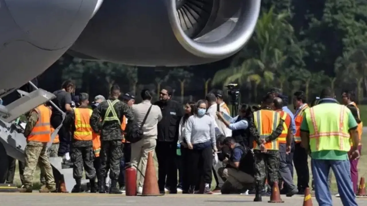 Personas con chalecos reflectantes y uniformes junto a la turbina de un avión en una pista de aterrizaje.