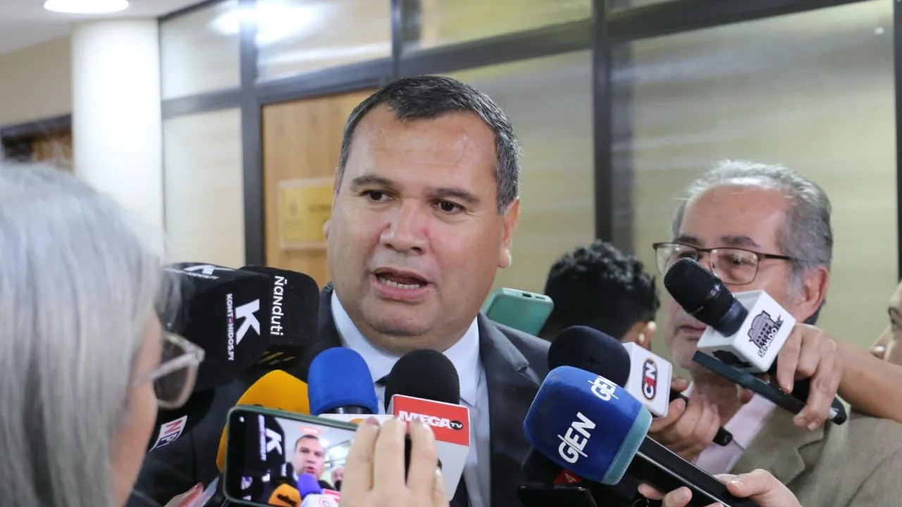 El senador Derlis Maidana brinda declaraciones rodeado de micrófonos de medios de prensa en un pasillo.