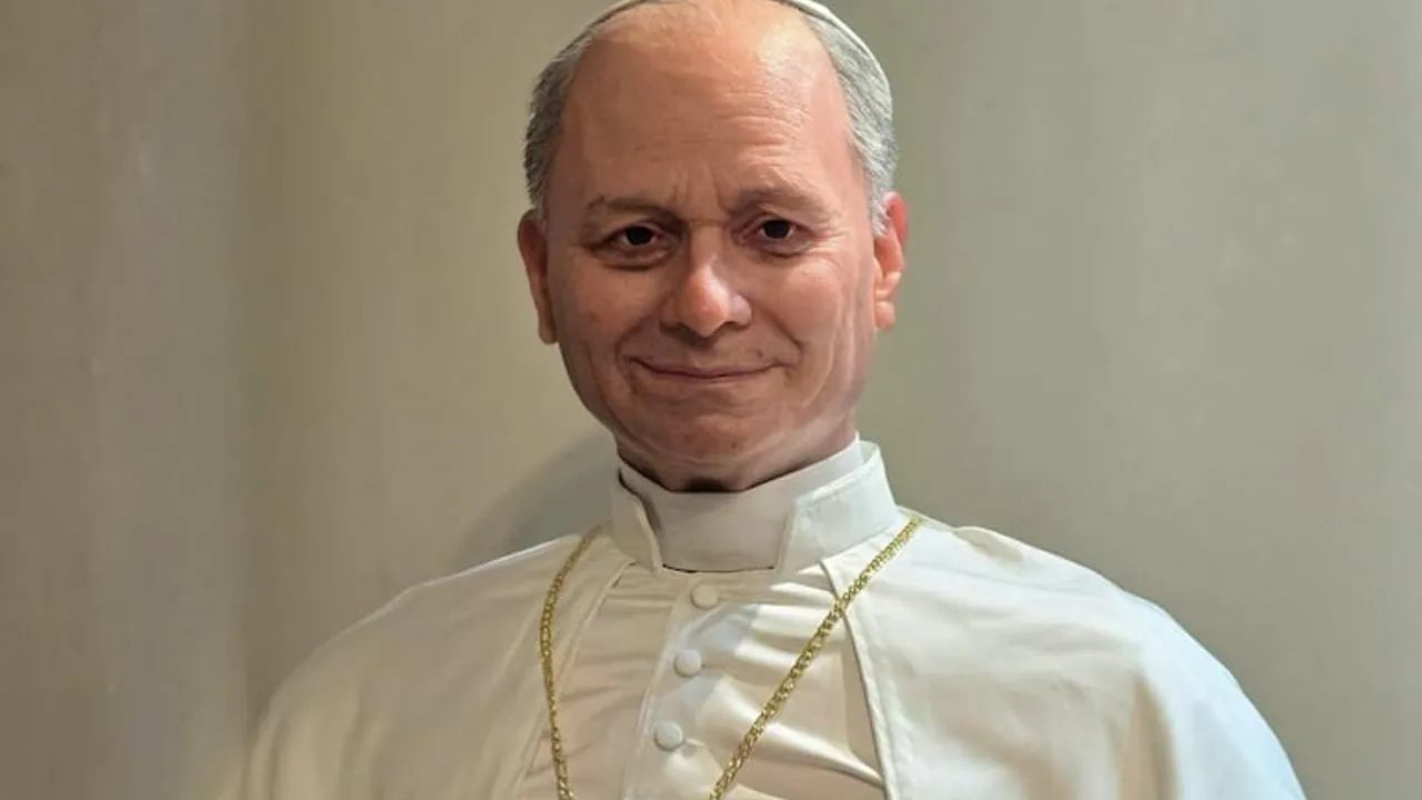 Estatua o busto de un papa sonriente vestido con sotana blanca y cadena pastoral dorada