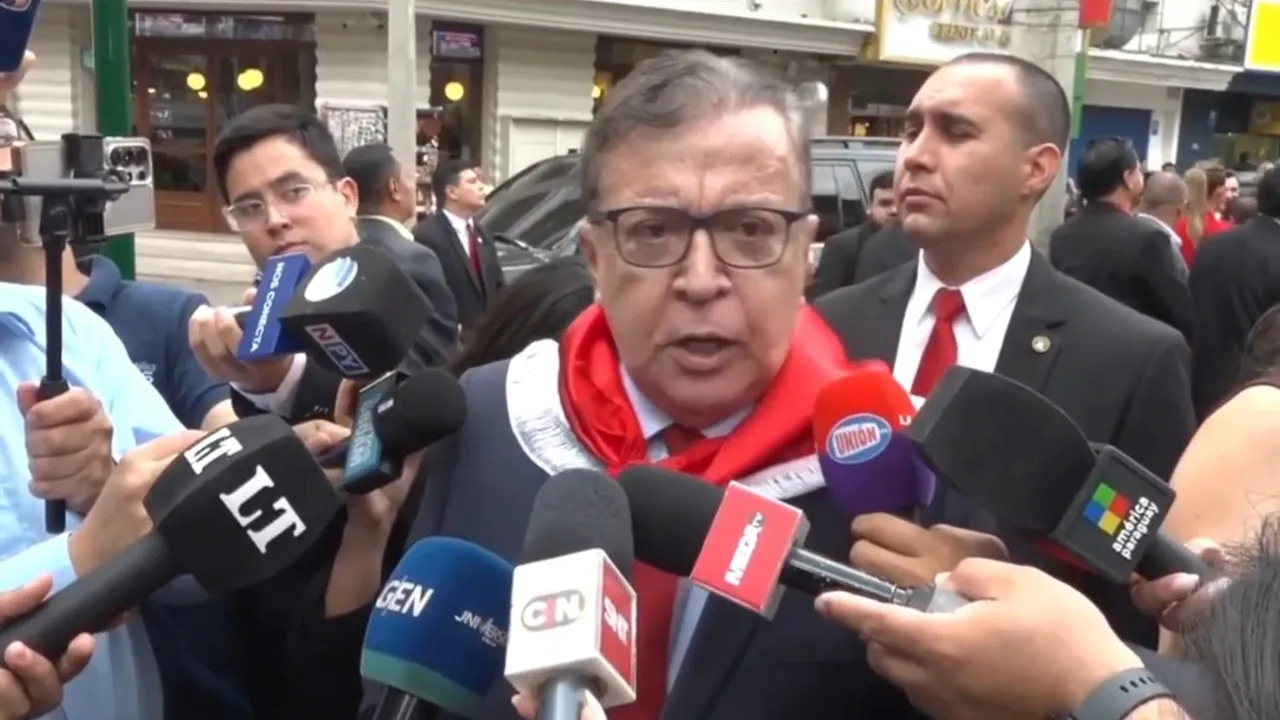 Nicanor Duarte Frutos con pañuelo rojo declara ante micrófonos de la prensa en una calle céntrica.