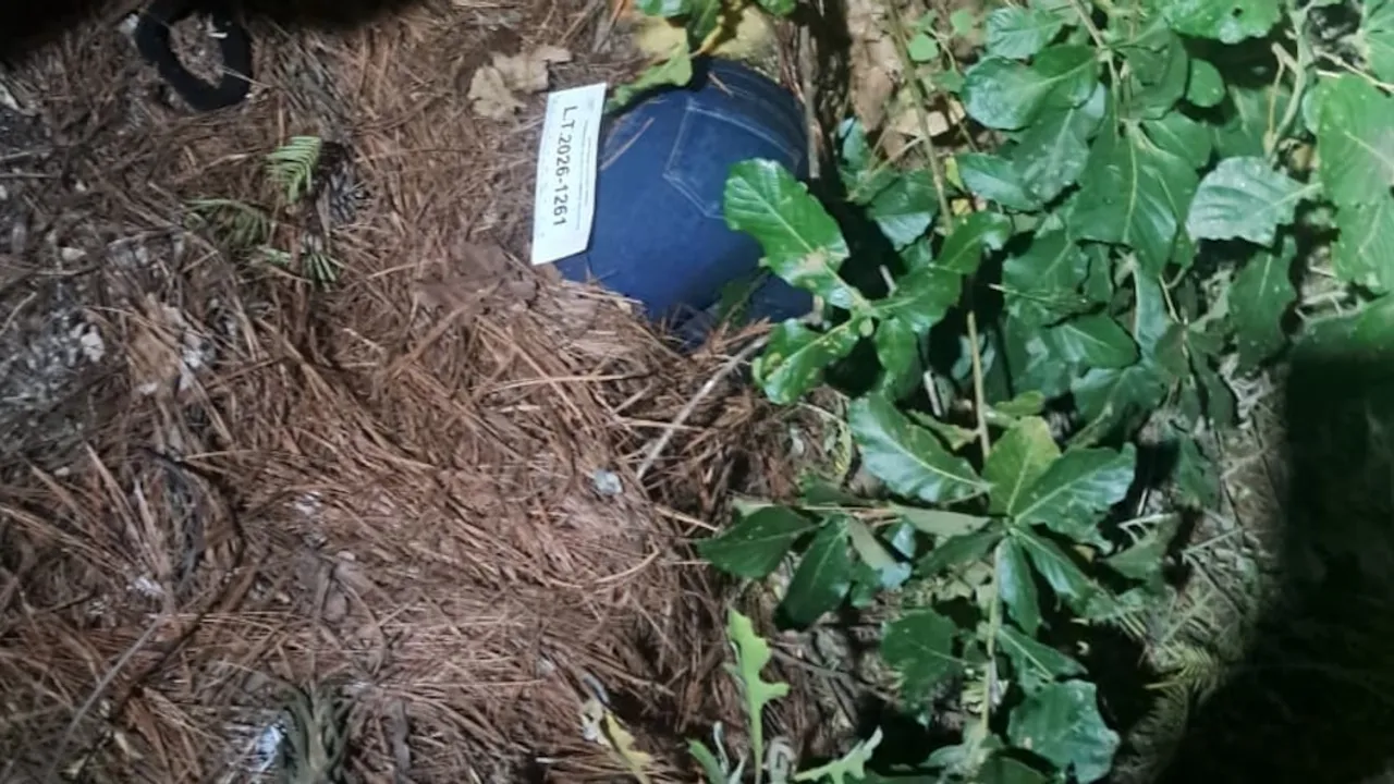 Evidencia policial con etiqueta numerada junto a una prenda de vestir en una zona boscosa.