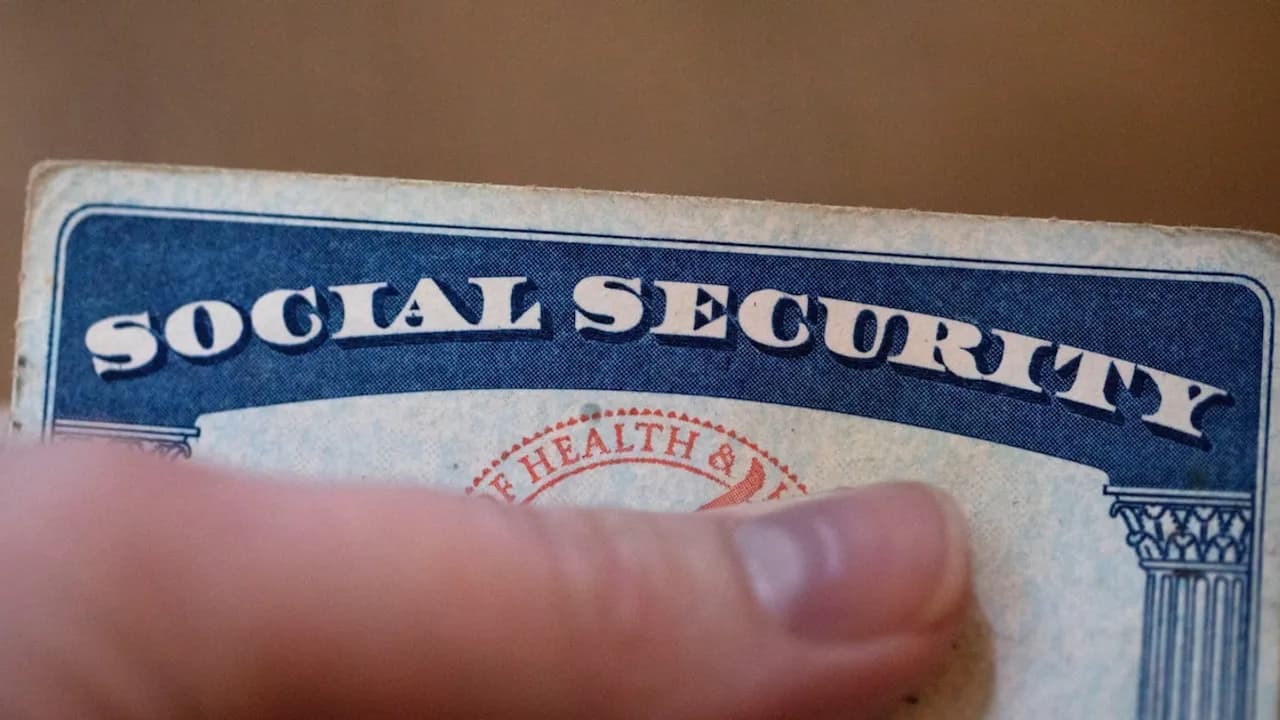 Primer plano de una tarjeta de Seguro Social azul y blanca sostenida con la mano de una persona.