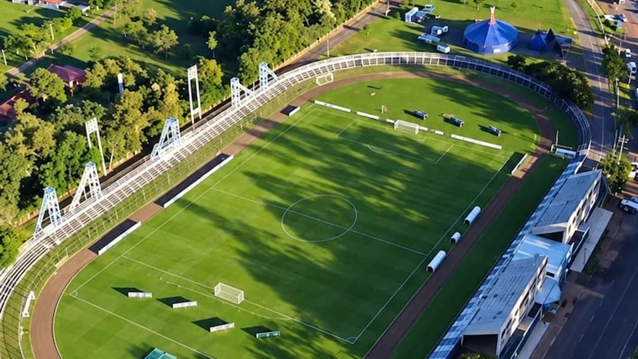 Vista aérea de un estadio de fútbol con césped verde, pista atlética circundante y torres de iluminación