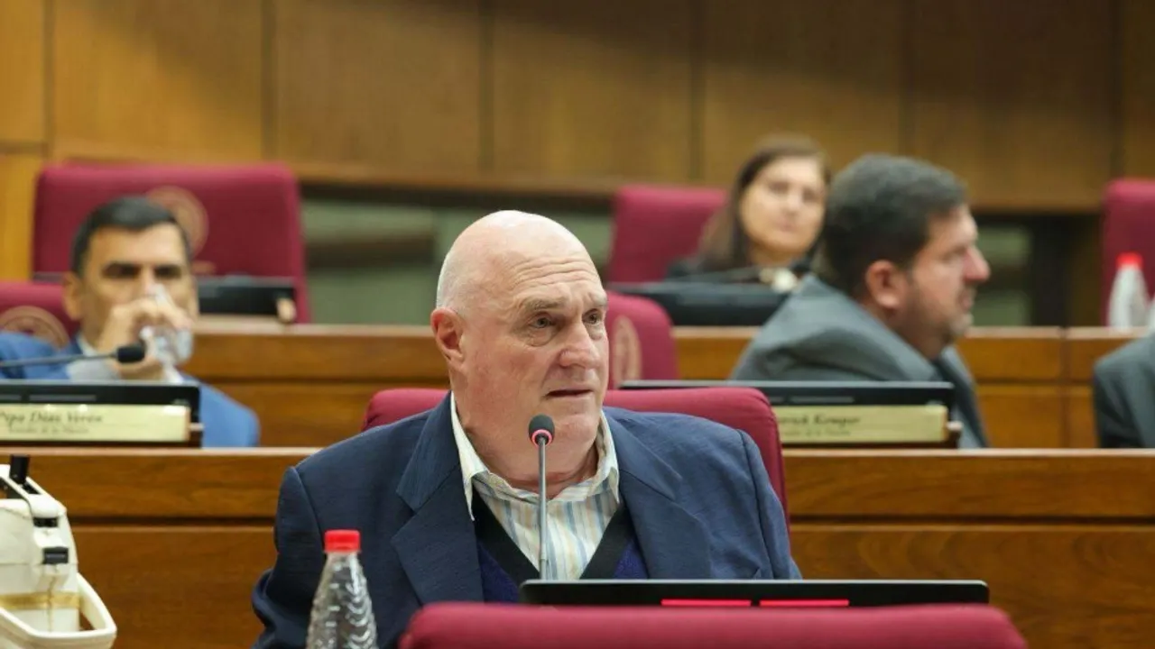 Hombre de traje azul y camisa a rayas hablando frente al micrófono en una banca del Senado