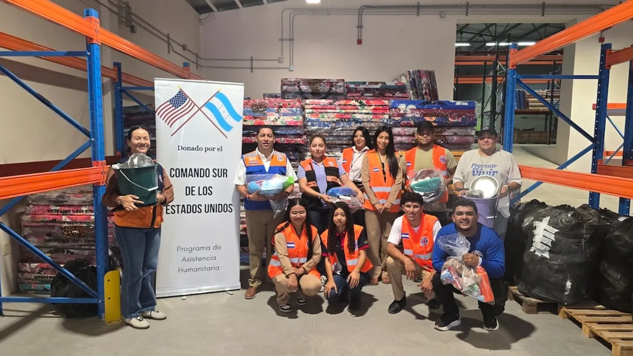 Trabajadores posan con suministros y colchones frente al cartel del Comando Sur en un depósito de ayuda.