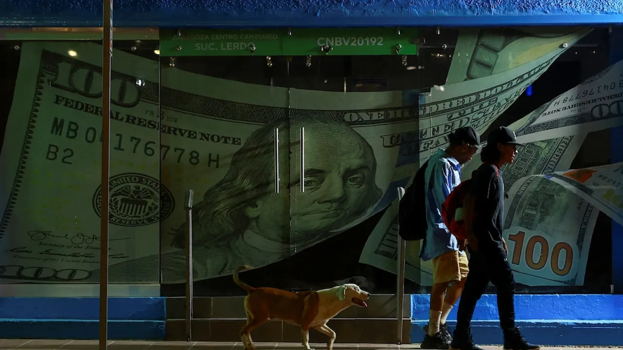 Dos personas caminan de noche frente a la vidriera de una casa de cambio decorada con un enorme billete de cien dólares.